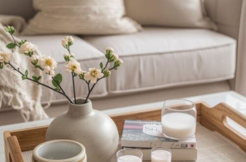 Coffee table styled for spring with fresh flowers, candle, and decorative tray, light-colored couch in the background