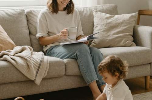 Mom sitting in a cozy living room, enjoying a quiet moment with coffee while her toddler plays nearby, showing realistic self-care for moms.